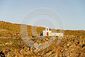 Old white abandoned Church Agios Ioannis on dramatic cliff on Kithnos Island, Greece, seen from the sea during golden hour