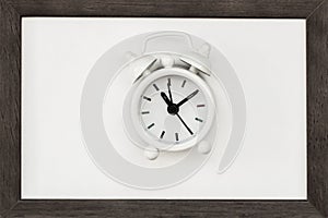 Old white alarm clock on wooden frame. Concept of time, deadline, countdown. Flat lay. Top view