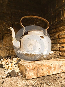 Old white battered kettle in a firebox