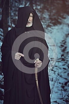 Old white beard pilgrim in dark forest with snow photo