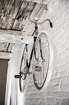 Old white bicycle whist on a white stone wall.