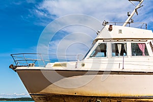 Old white boat shot sidewise against blue sky