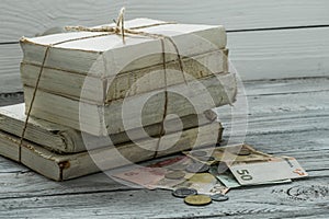 Old white books with money and coins on wooden background