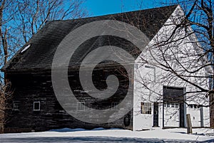 Old white and brown New England barn in a snowy field