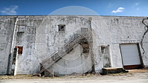 Old white commercial building with sky and clouds.