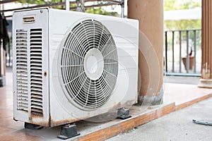 The old white compressor is  outside the building