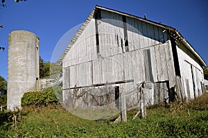 Old white deteriorating barn and silo