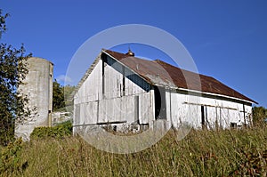 Old white deteriorating barn and silo
