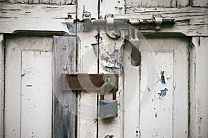 Old white door with rusty latch locked with steel key