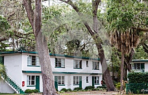 Old White and Green Hotel Behind Oaks