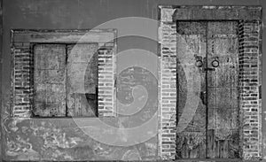 Old white and grey brick wall of ancient building. Concrete and brick building with closed wooden door and window. Exterior of old