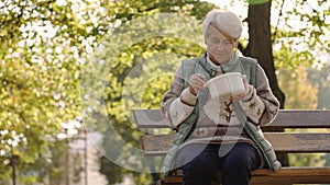 Old white-haired homeless woman eating warm meal thanks to the charity volunteers that help people in need.