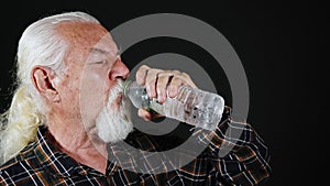 Old White Haired Man is Drinking Water From Plastic Bottle