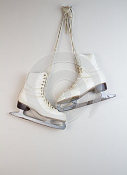 Old white ice skates hanging on the wall