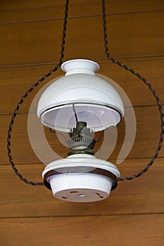 Old white lamplight hanging beside a wooden wall.