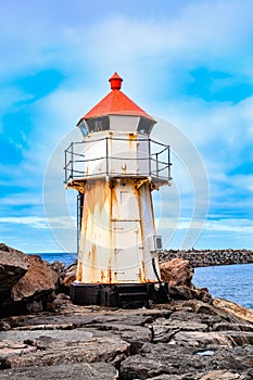 An old white lighthouse with orange roof