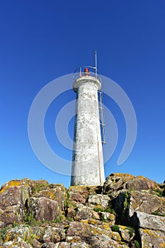 Old white lighthouse on the rocks with blue sky. Muxia, Spain.