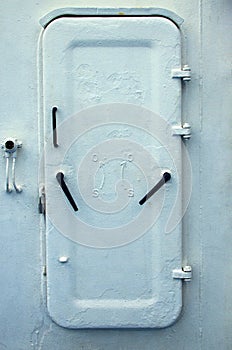 Old white metal door onboard ferry ship. White watertight ship door with black door handles. Iron door closed
