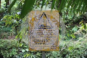 Old and with white moss overgrown sign warning for deep water