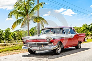 Old white-red classic american retro car on the road in countryside, Trinidad, Cuba