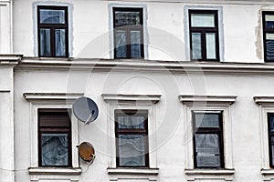 Old white residential building with grass windows and satellite dish