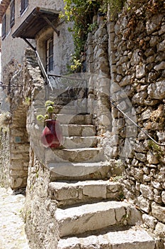 Old white rock staircase and iron fence leading to a home covered in green vines in Eze France
