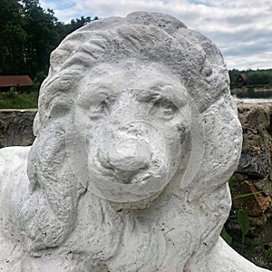 old white statue of a lion face on background forest