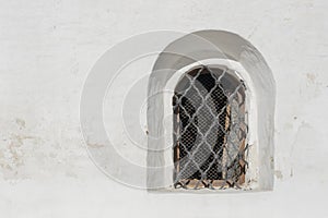 Old white stone wall with one grating window