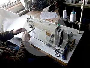 Old white vintage hand sewing machine. A man is sewing