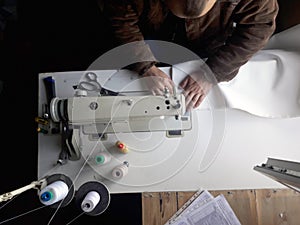 Old white vintage hand sewing machine. A man is sewing