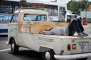 old white Volkswagen T1 pickup van with a man sleeping behind