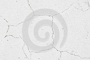 An old white wall with a cracked texture is decorated with cement mortar