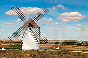 Old white windmills, made of stone, on the field with blue sky and white clouds. La Mancha, Castilla, Spain photo