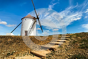 Old white windmills, made of stone, on the field with blue sky and white clouds. La Mancha, Castilla, Spain photo