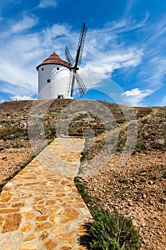 Old white windmills, made of stone, on the field with blue sky and white clouds. La Mancha, Castilla, Spain photo