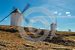 Old white windmills, made of stone, on the field with blue sky and white clouds. La Mancha, Castilla, Spain photo