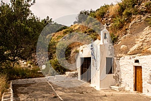 Old whitewashed small christian church built in a rock on a hill on Milos Island near Trypiti town, Greece