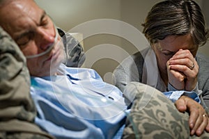 Old wife praying for terminally ill husband
