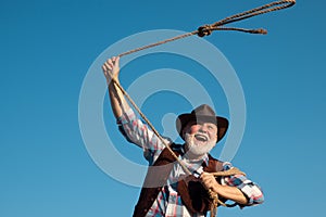 Old wild west cowboy with lasso rope. Bearded western man with brown jacket and hat catching horse or cow.