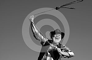 Old wild west cowboy with lasso rope. Bearded western man with brown jacket and hat catching horse or cow.