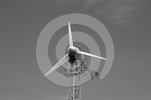 Old wind turbine against blue sky. Black and white