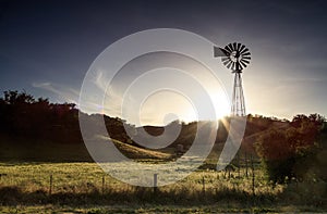 An old windmill in a field at sunset.