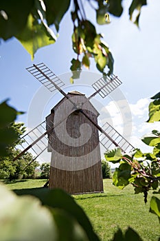 Old windmill on a hill in the rays of the sun at sunset, green fields. Spring rural landscape with an old mill. Stary Podvorov, So