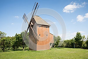 Old windmill on a hill in the rays of the sun at sunset, green fields. Spring rural landscape with an old mill. Stary Podvorov, So