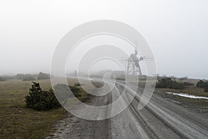 Old windmill by roadside in the mist