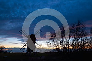 Old windmill silhouette by a cloudy sky