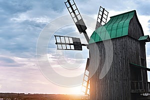 Old windmill standing alone in the field with the blue sky on the background