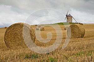 Old windmill in a straw bales field in France