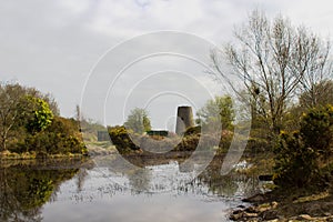An old windmill stump reflected in the still water of the lake in the derelict 19th century lead mines in Conlig Northern Ireland