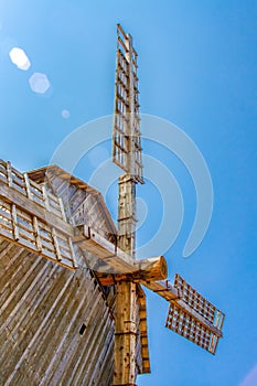 Old windmill. View of wooden wings of windmill from below against the blue sky. Vertical photo